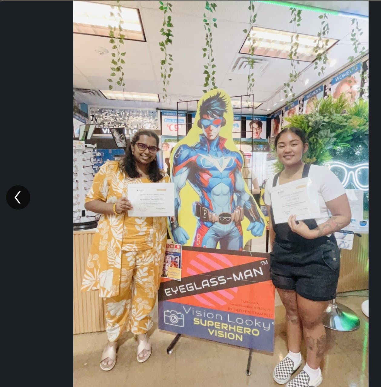 Vision Looky Studio cohort at graduation, holding certificates outside the flagship storefront.